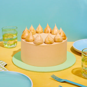 Pastel-colored cake with decorative elements on a yellow table with blue background