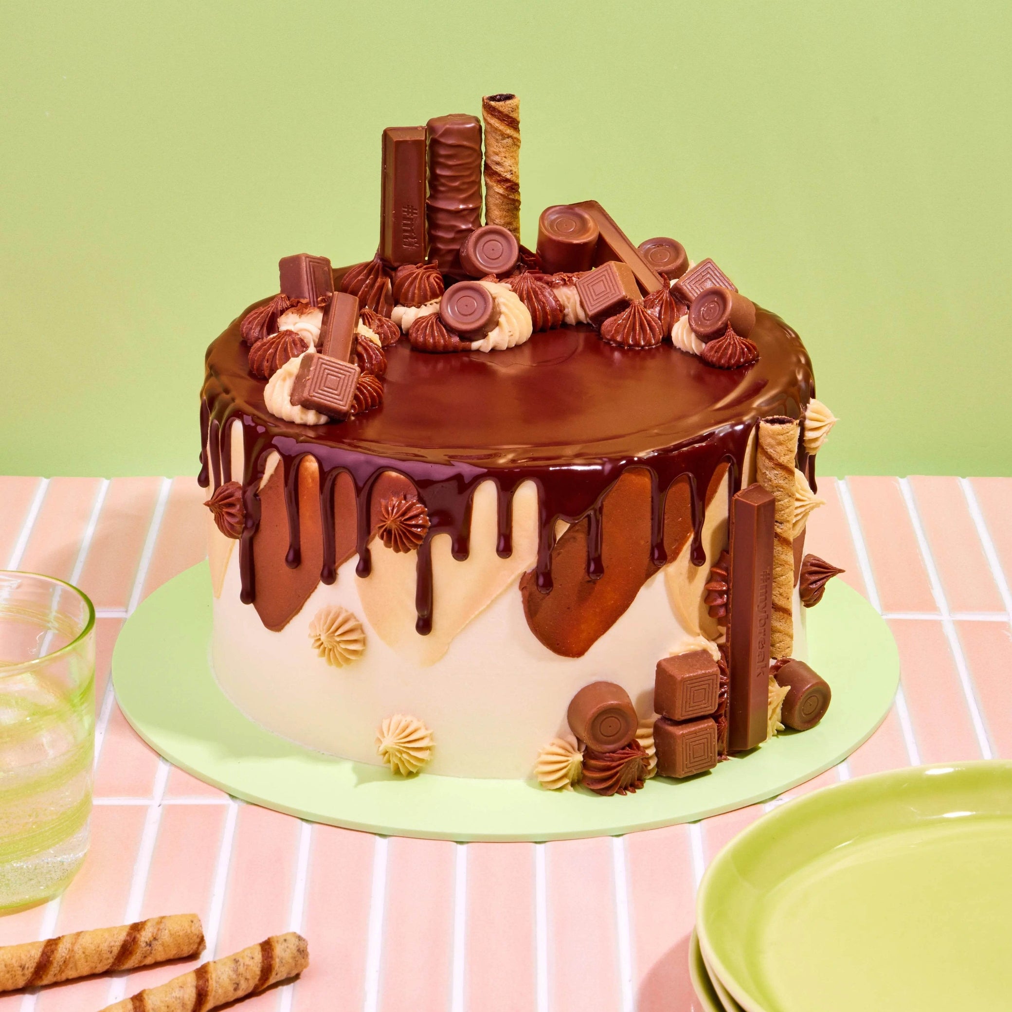 Tuck Shop Cake decorated with chocolate ganache drip and topped with Rolos, Twix, Kit-Kats, and Munchies chocolates.