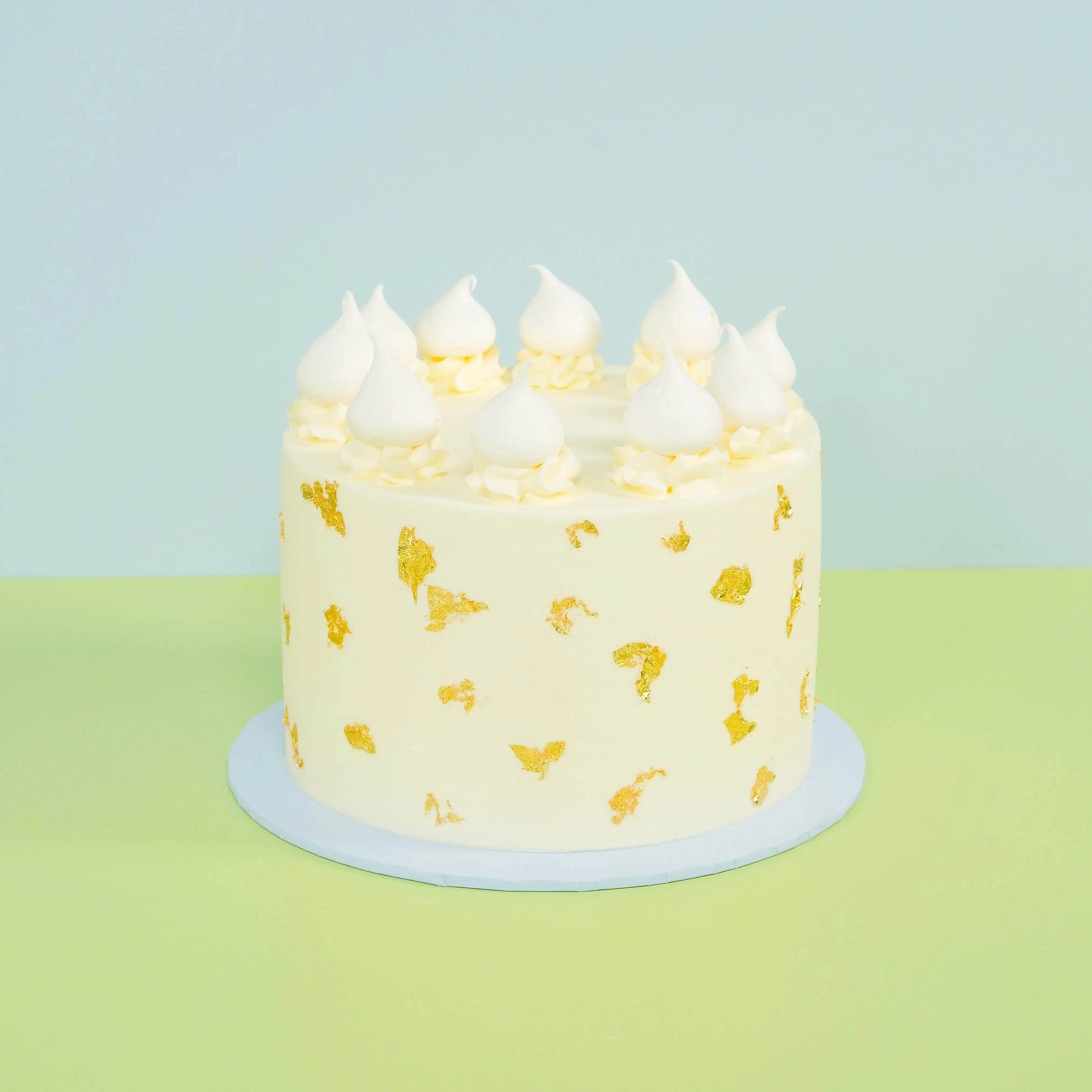 White Gold Wedding Cake with smooth white buttercream, real edible gold leaf, and delicate meringue toppings by Crumbs & Doilies.