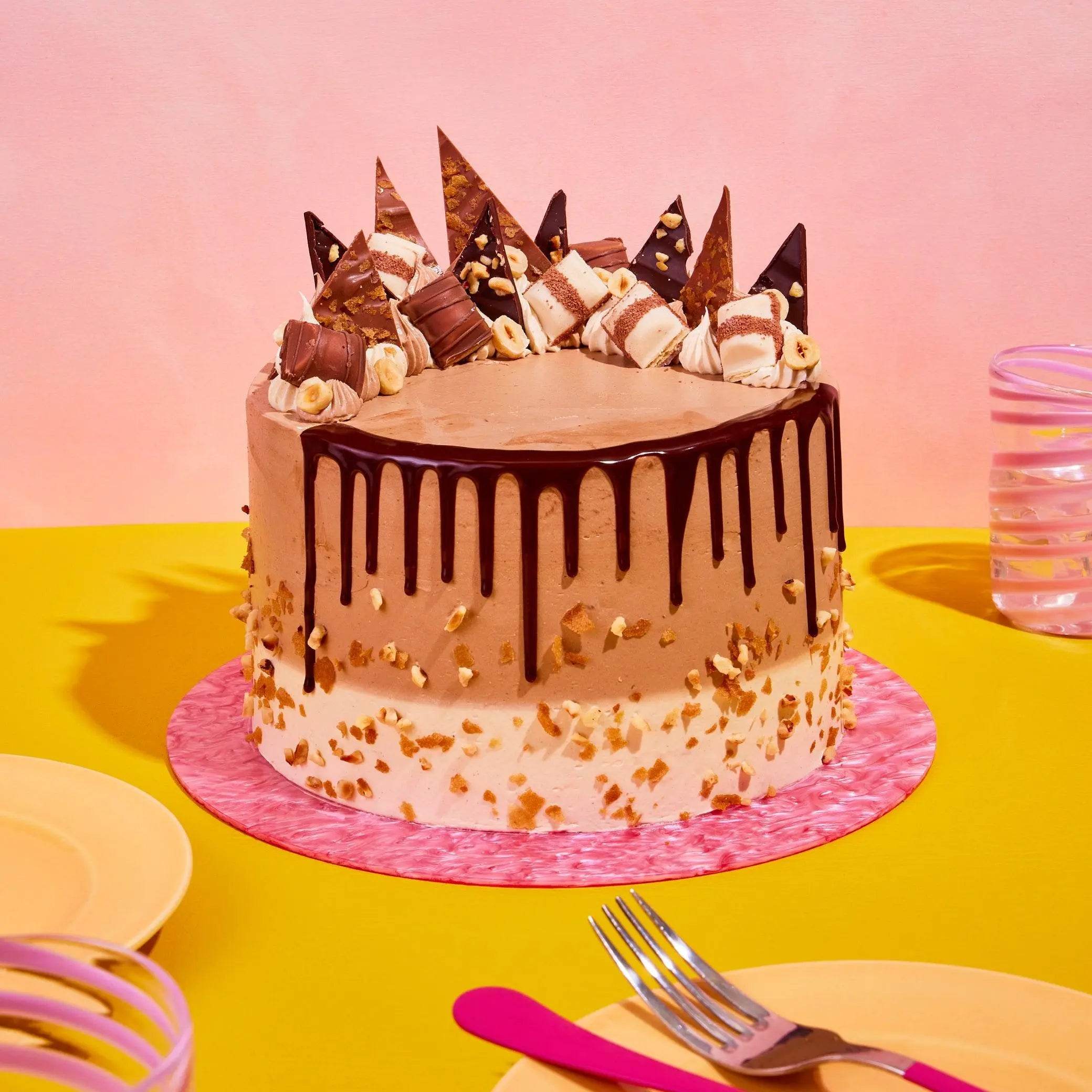 Bueno Cake by Crumbs & Doilies with chocolate ganache drip, Kinder Bueno pieces, and hazelnut sponge layers.