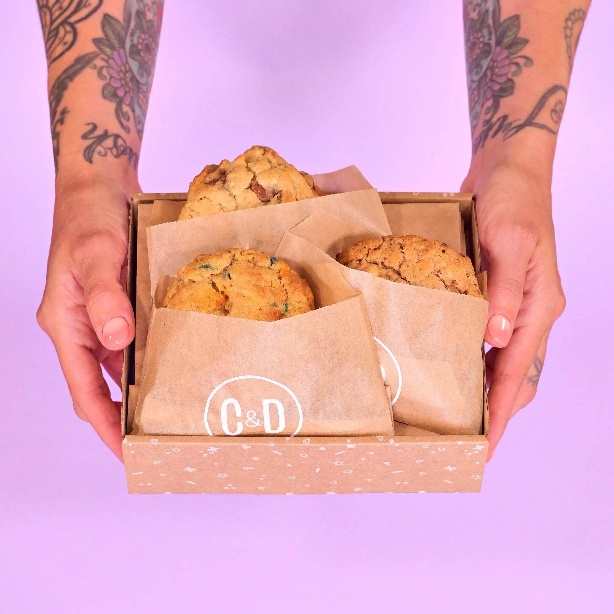 3 x New York Cookies, The Birthday Box held in hands with Crumbs & Doilies packaging