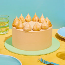 Pastel-colored cake with decorative elements on a yellow table with blue background