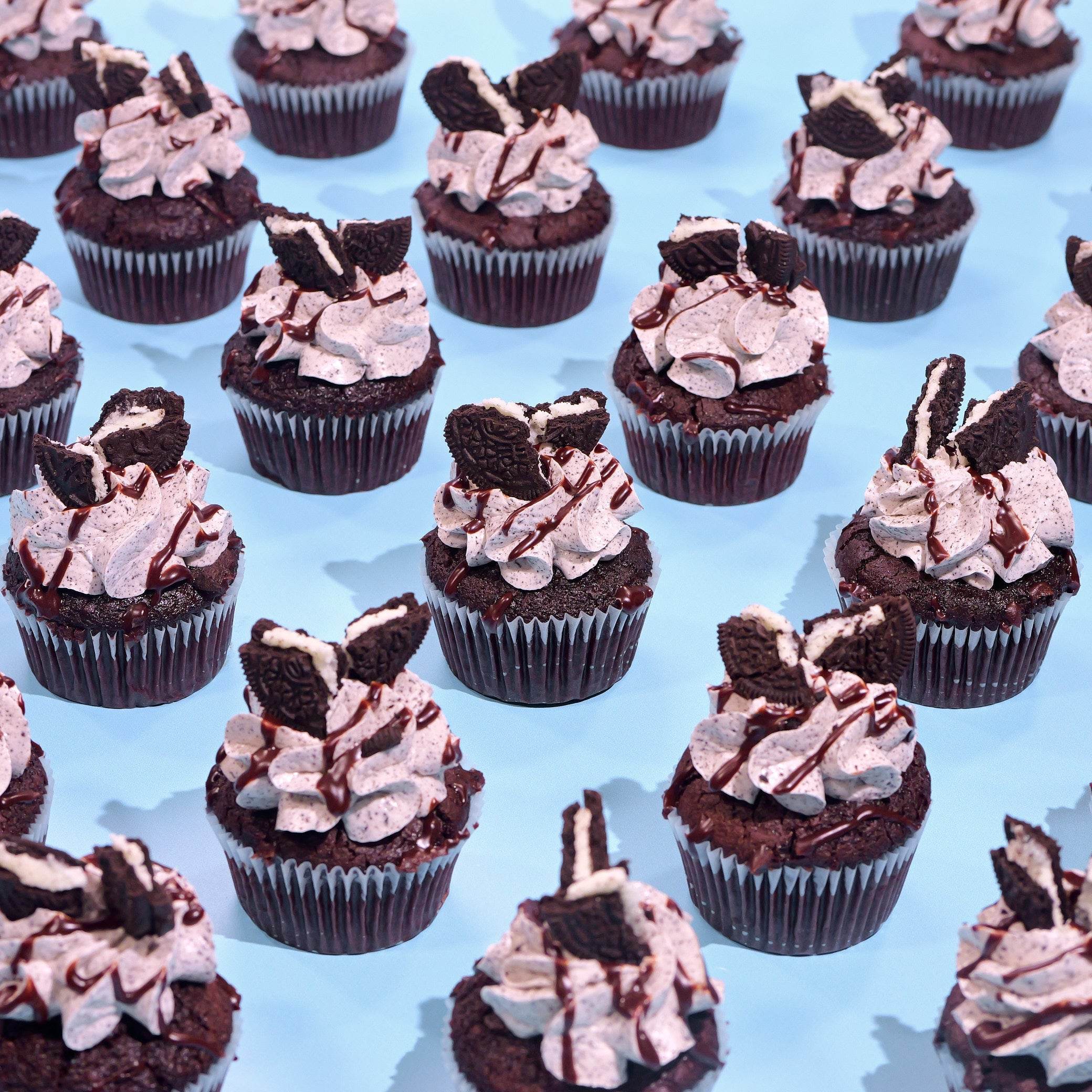Oreo Cupcakes with black cocoa sponge, cookies and cream icing, ganache drizzle, and Oreo cookie topping Crumbs & Doilies