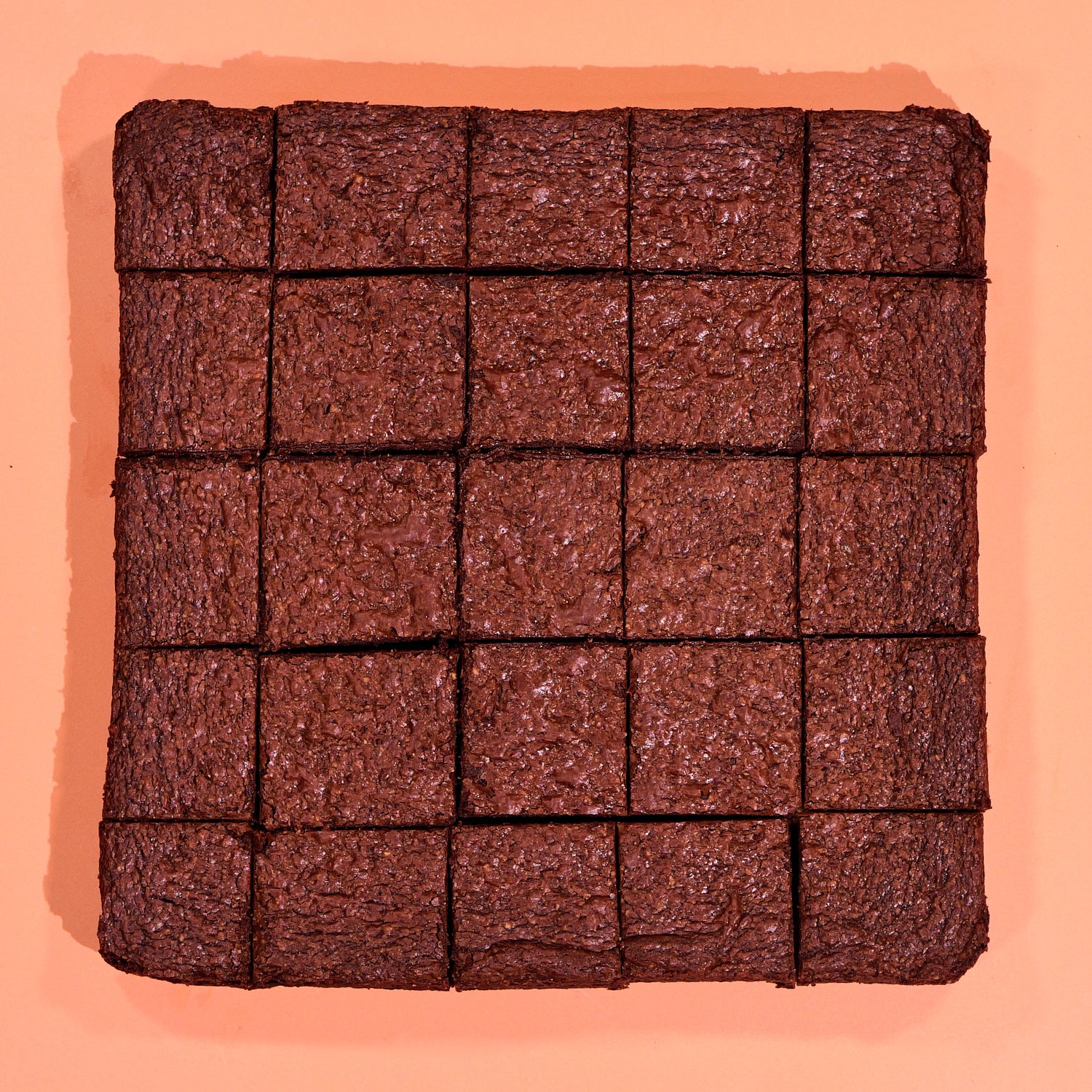 Gluten Free Almond Flour Brownie cut into squares and arranged on a peach background for sharing