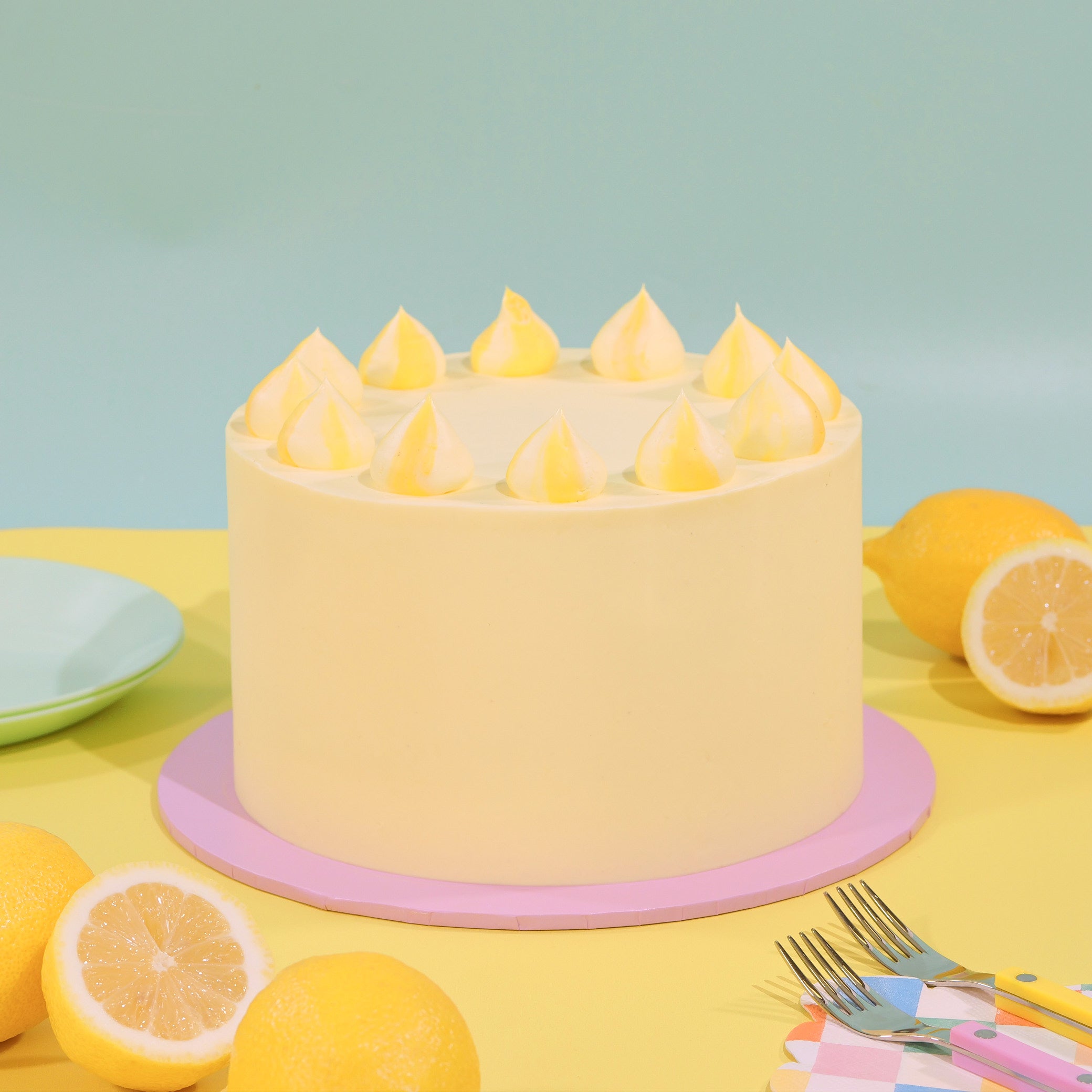 Classic Lemon Drizzle Cake with lemon buttercream decoration and fresh lemons by Crumbs & Doilies