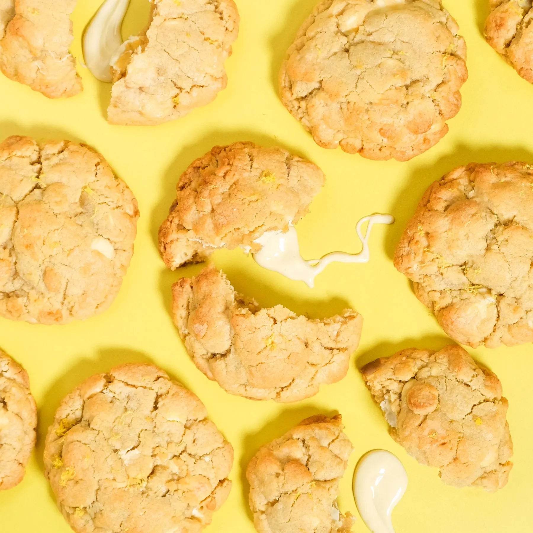 Lemon Meringue New York Cookie with white chocolate chunks and zesty lemon on a bright yellow background by Crumbs & Doilies.