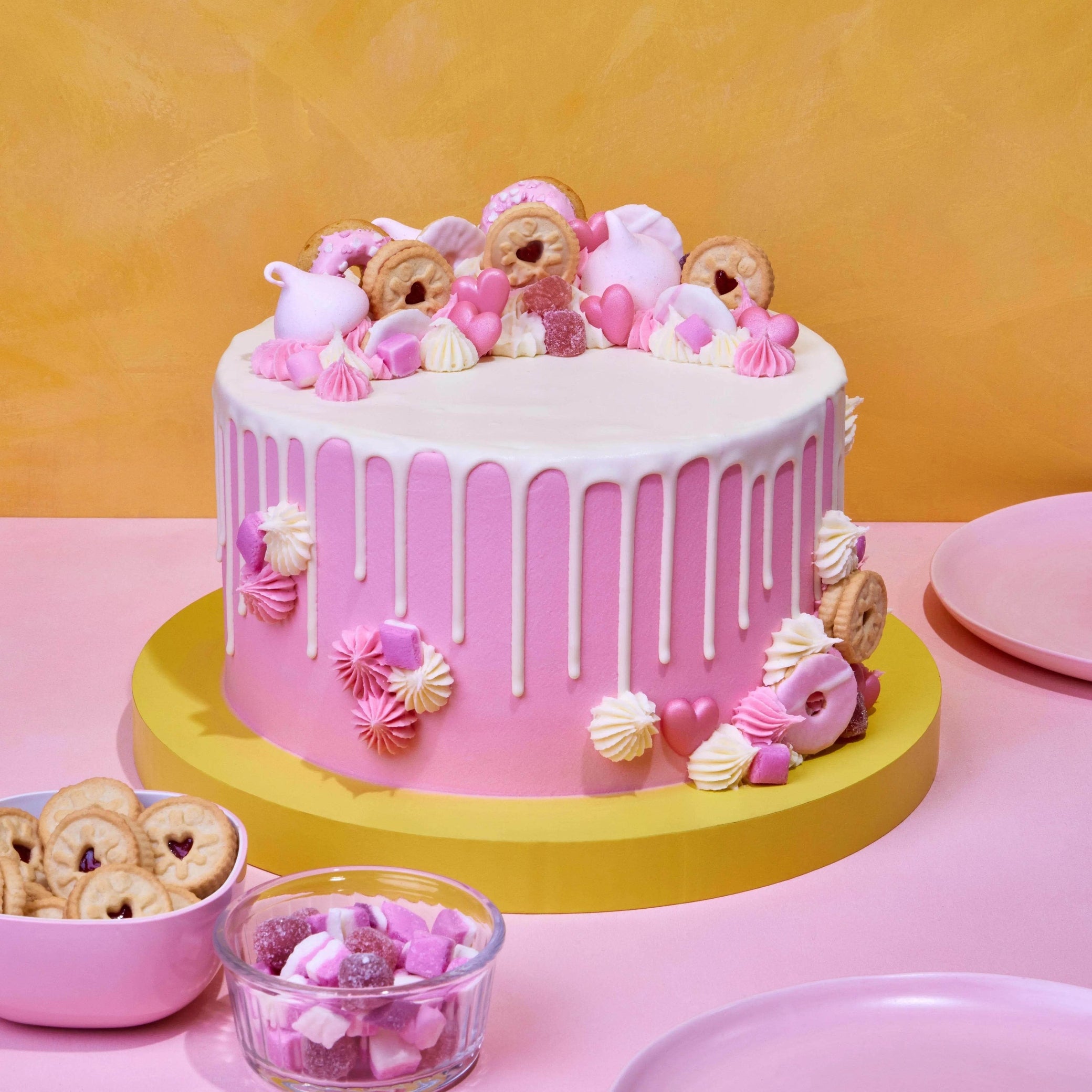 Pretty In Pink Cake with white chocolate drip, pink meringues, Jammy Dodgers, and vanilla buttercream decoration.