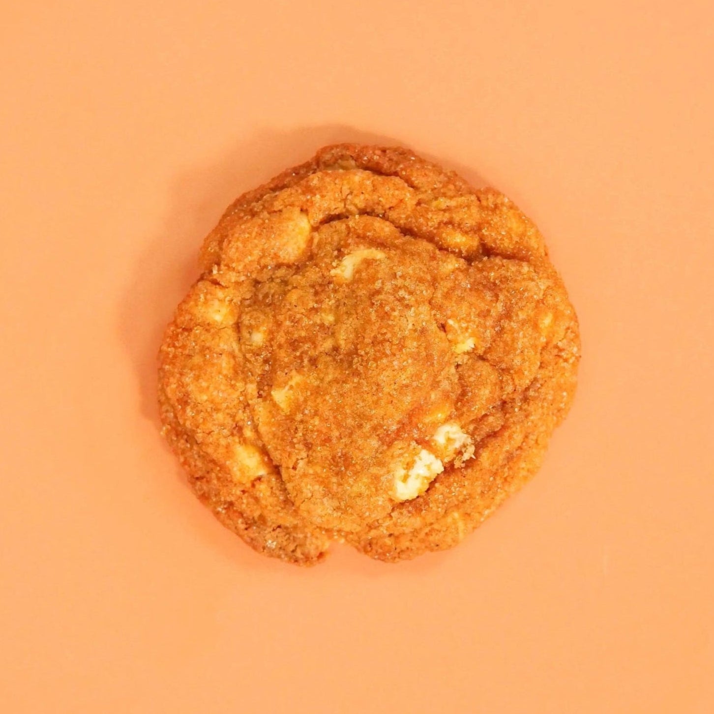 Pumpkin Spiced New York Cookie by Crumbs & Doilies with white chocolate and warm autumn spices on orange background