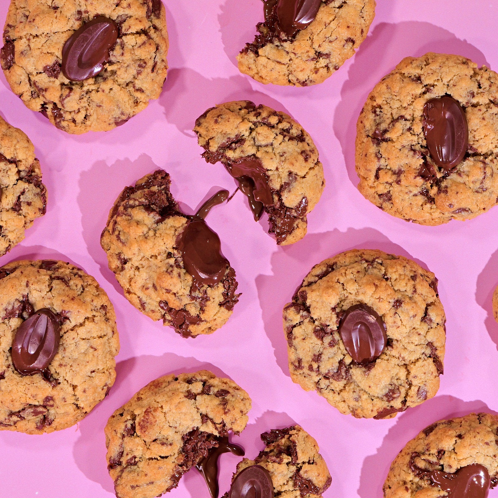 Ltd Edition Valrhona Choc Chip New York Cookie with melted chocolate center arranged on pink background