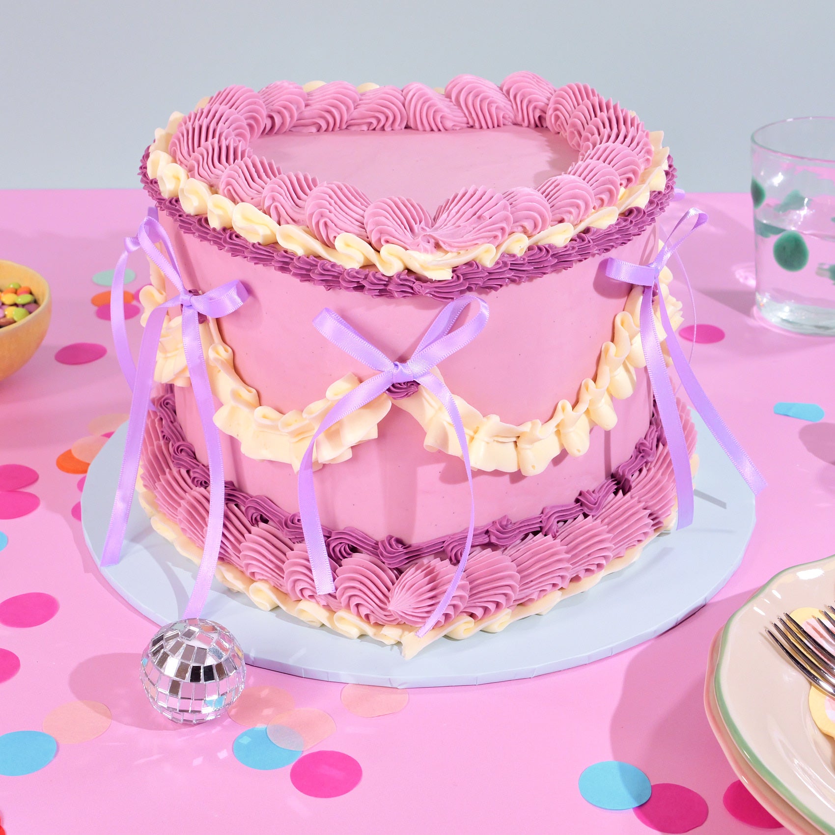 Vintage Heart Cake with pink and cream piped Swiss Meringue buttercream and purple ribbon bows, gallery position 1 view