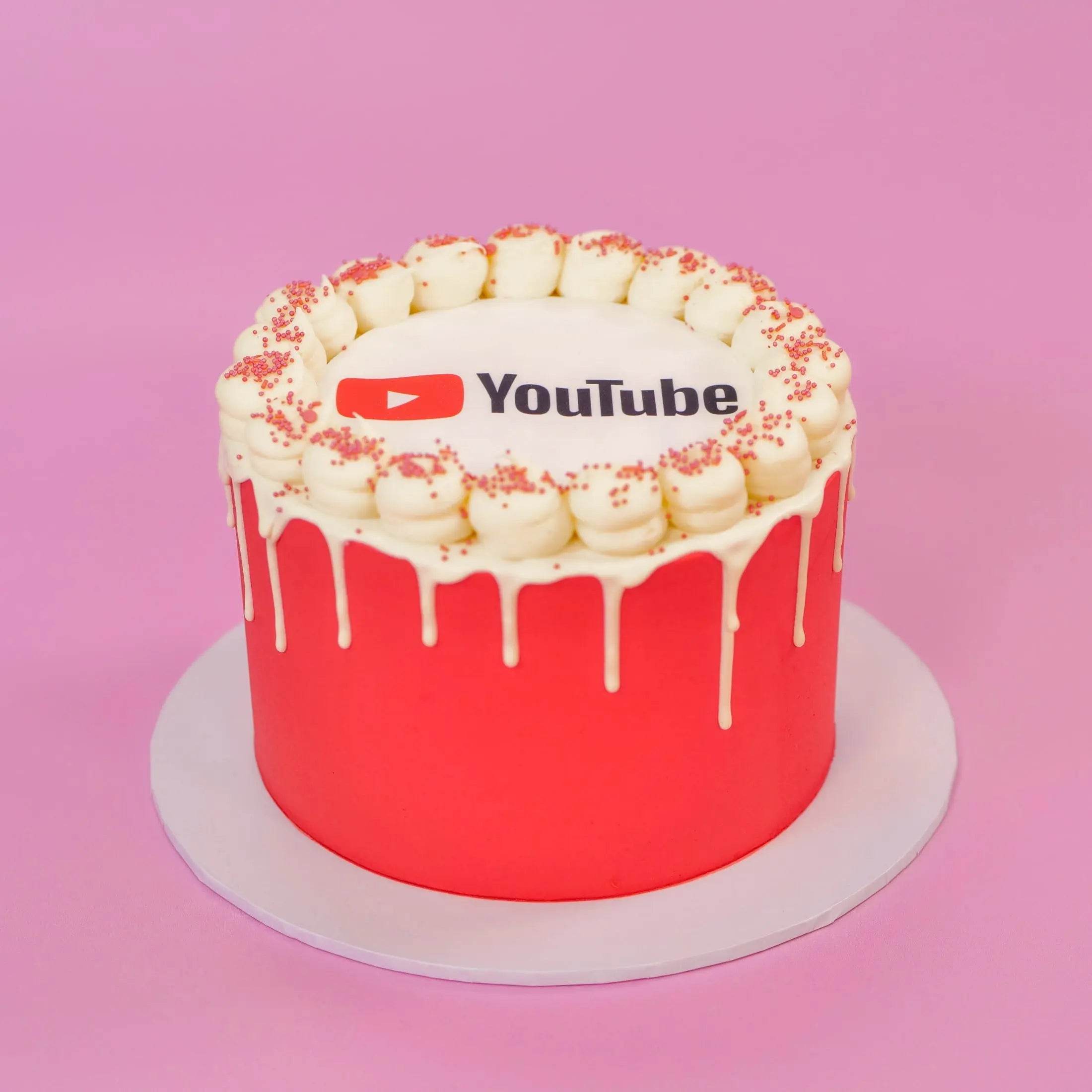 Corporate Drip Cake with Logo featuring white drip icing and edible YouTube logo plaque Crumbs & Doilies