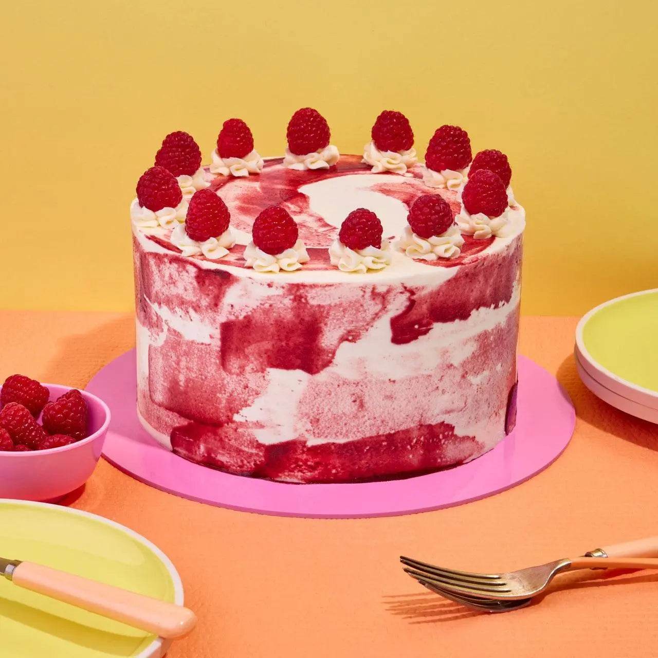 Raspberry Ripple Cake by Crumbs & Doilies with raspberry swirl icing and fresh raspberries on top.