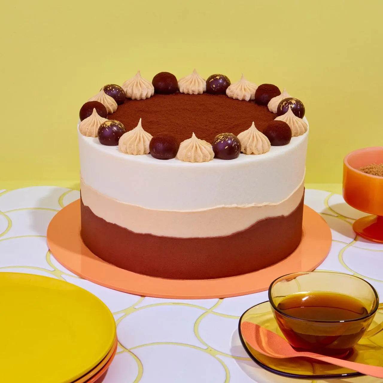 Tiramisu Cake with layered coffee sponge, mascarpone cream, chocolate buttercream, and gold-flecked truffle decorations.